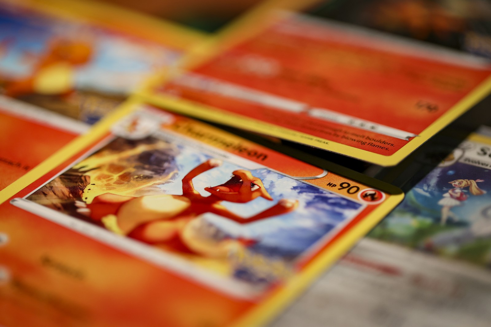 Primer plano de cartas Pokémon en inglés superpuestas, con una carta de Charizard en primer término