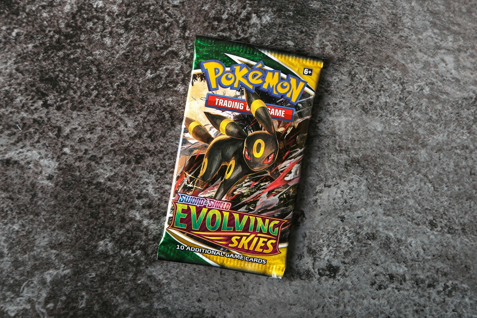 Sobre inglés Pokémon Evolving Skies con Umbreon sobre una superficie gris; imagen ilustrativa.